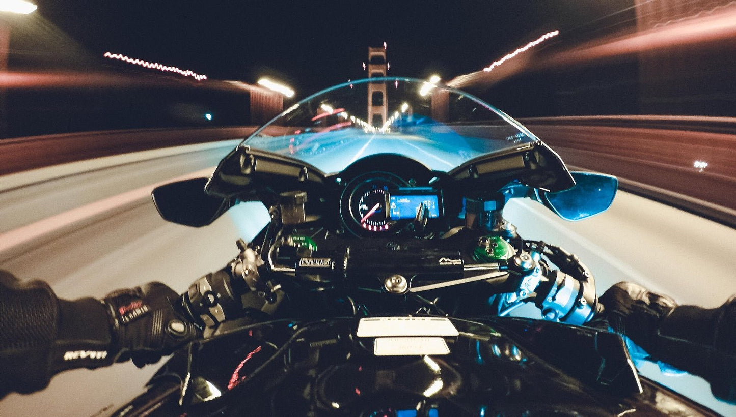 Vista desde motocicleta en movimiento cruzando un puente de noche, efecto de velocidad
