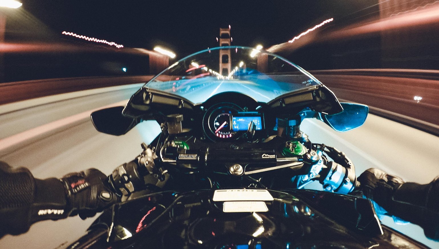 Vista desde motocicleta en movimiento cruzando un puente de noche, efecto de velocidad