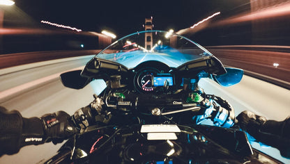 Vista desde motocicleta en movimiento cruzando un puente de noche, efecto de velocidad